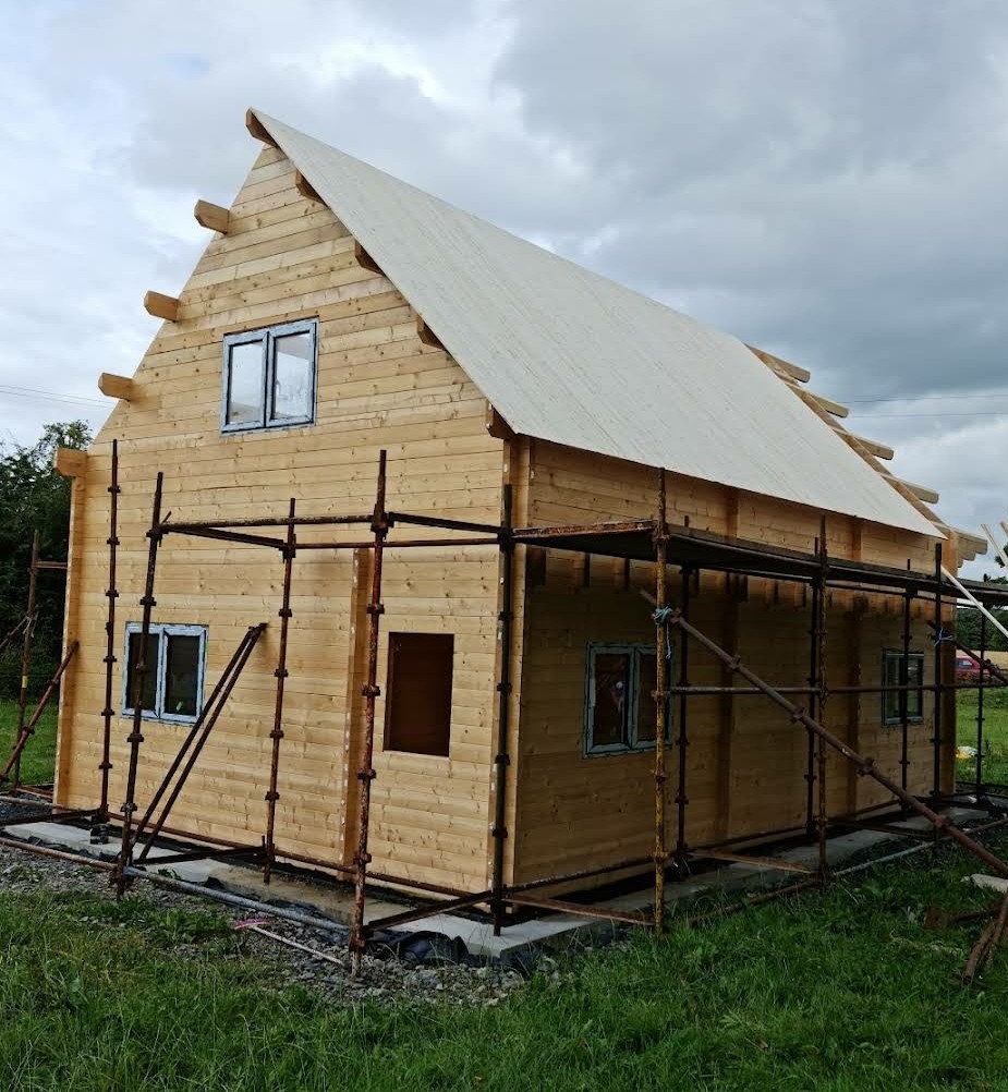 A timber frame house with scaffold around it being constructed.